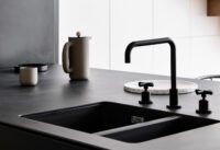 Matt Black tapware with a kitchen mixer and separate controls over a dark double sink in a modern kitchen.