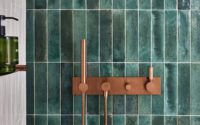Tuscan Bronze PVD tapware with bath and shower controls set against deep green and white tiled walls.